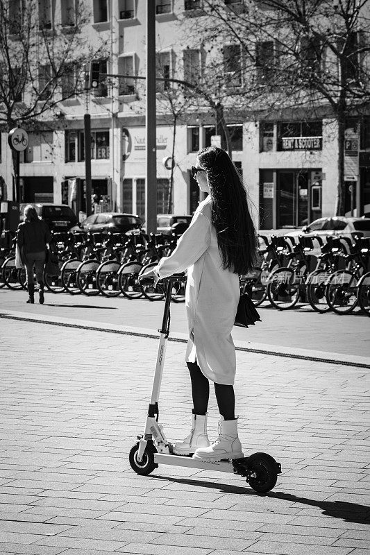 一个女人在人行道上骑着电动滑板车。