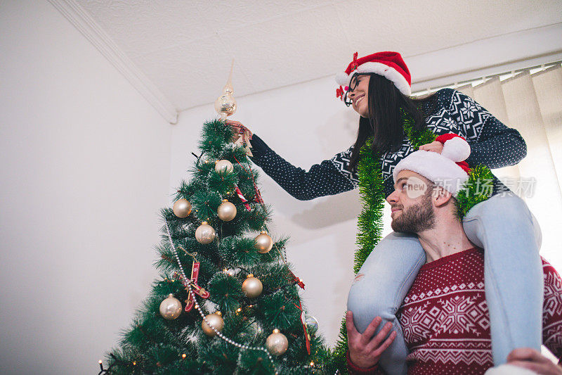 可爱的年轻夫妇装饰圣诞树