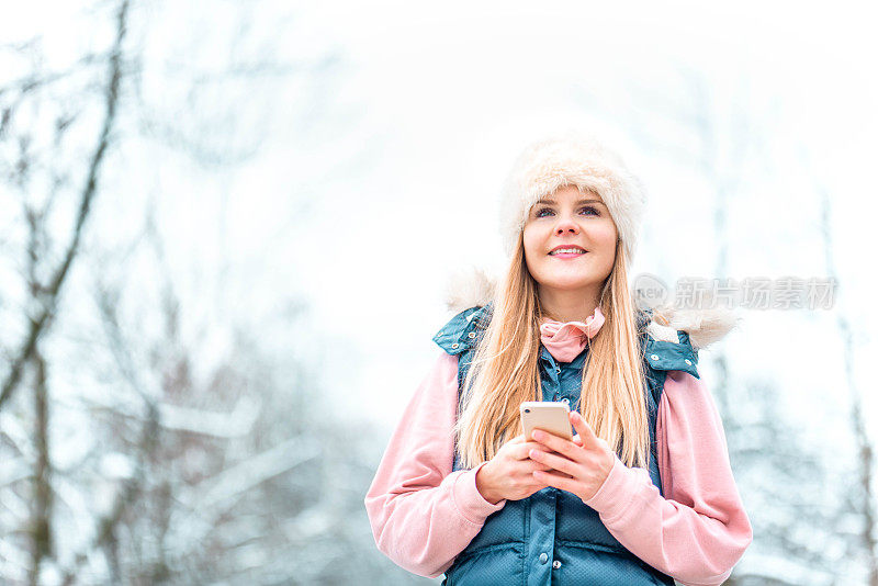 一个女人在下雪的冬天用手机