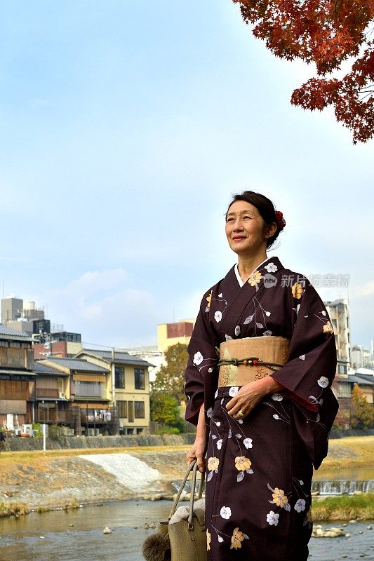 穿着和服的日本妇女在京都的秋天沿着加茂河行走