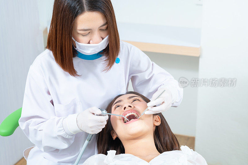 牙科医生在牙科诊所检查一名亚洲女病人的牙齿