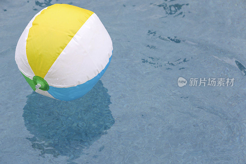 在清爽的游泳池水中漂浮的沙滩球。