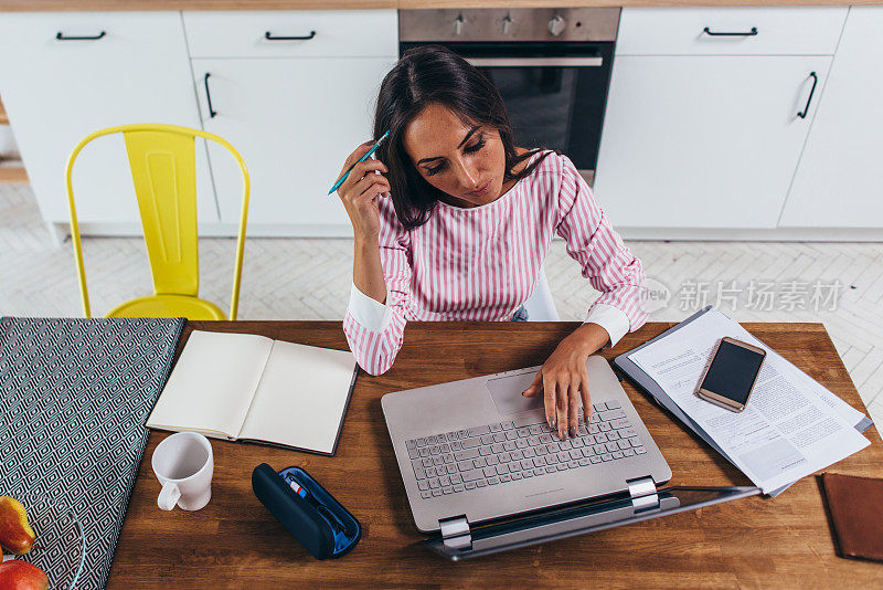 女性自由职业者在家里用笔记本电脑工作。俯视图