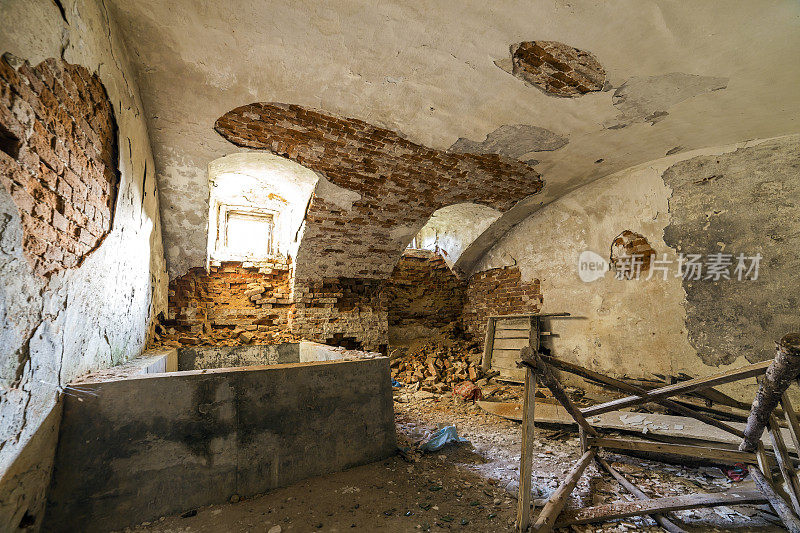 古老建筑或宫殿的废弃废弃的空地下室，灰泥墙开裂，低矮的拱形天花板，带铁条的小窗户，肮脏的地板。
