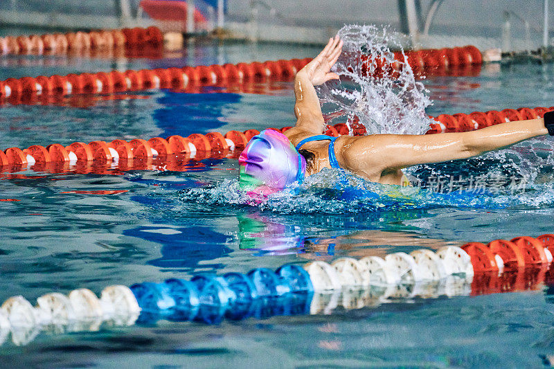 女运动员蝶泳式游泳。水花四溅向不同的方向。