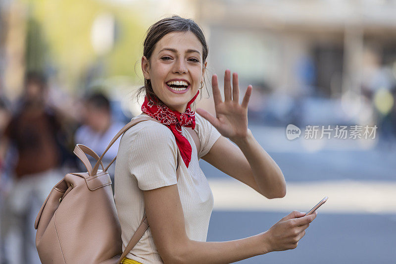 一名年轻女子正带着她的智能手机走在城市的路上