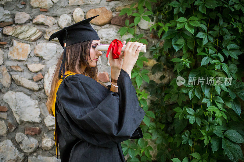 肖像特写美丽的毕业生毕业的学生女孩年轻的女人在帽子长袍显示持有文凭庆祝毕业典礼的概念