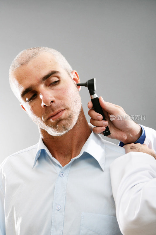 一个耳朵里插着耳镜的男人正在体检