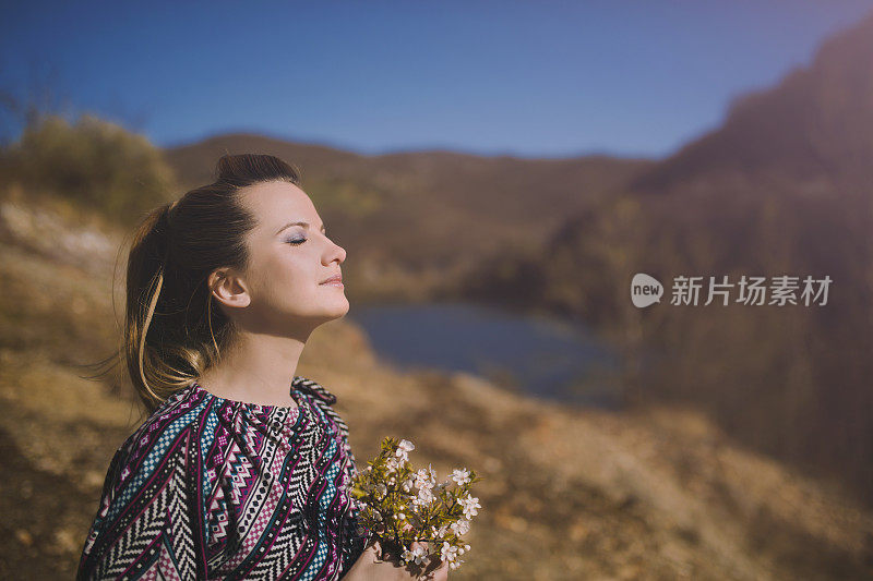 女人带着春天的花在山上的湖