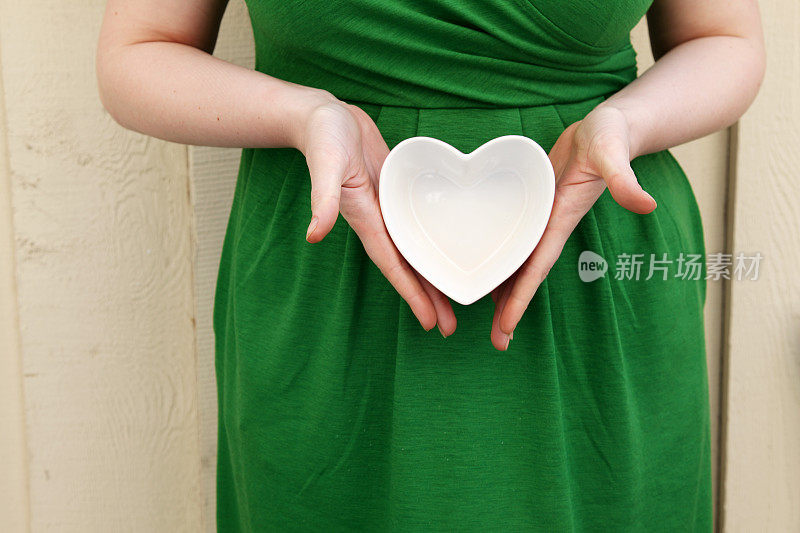 穿着绿色裙子的女人露出白色的心型纸