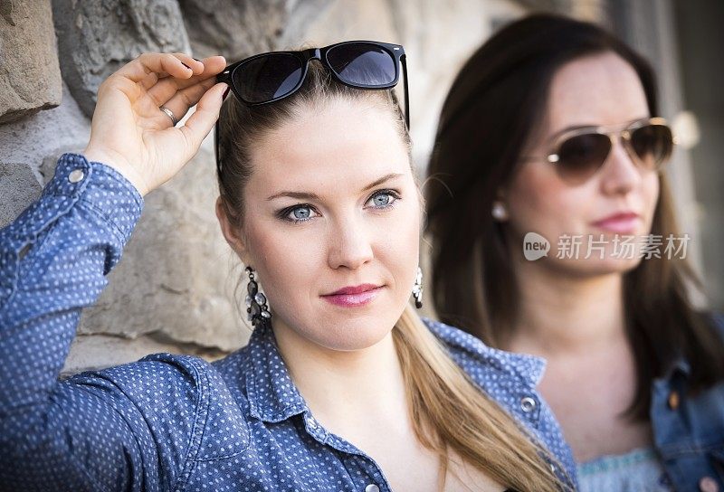 两个戴着墨镜的漂亮女人朝一个方向看