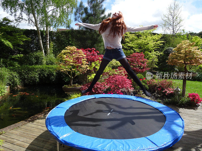 一个没有安全网的女孩在花园里的蹦床上蹦跳