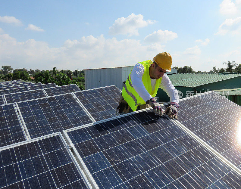 年轻的维修工人正在屋顶上安装太阳能电池板