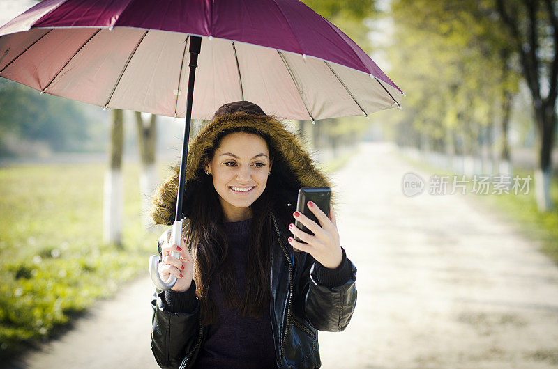 年轻女子在雨中用手机发短信