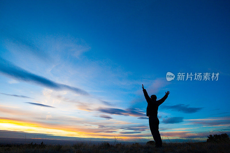 剪影的男人举起手臂进入日落的天空景观