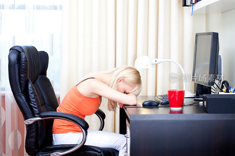 疲惫的女人睡在家里的电脑桌上