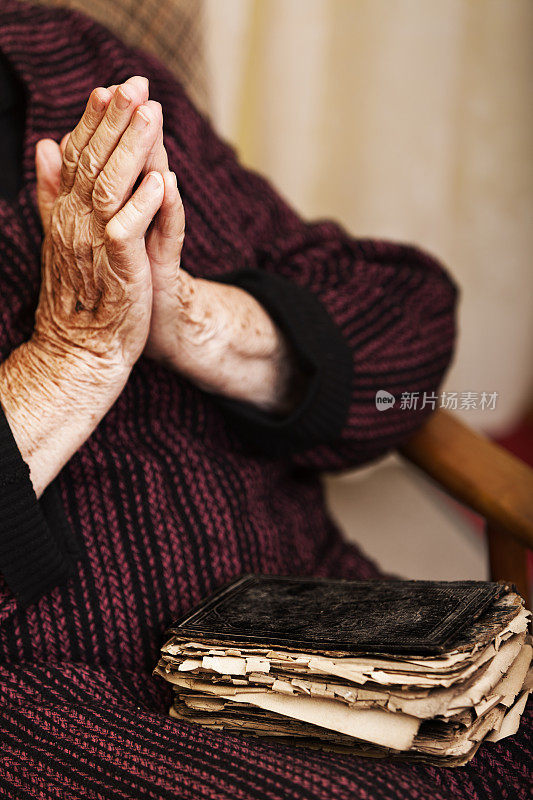 老妇人在祈祷，膝盖上放着一本旧书