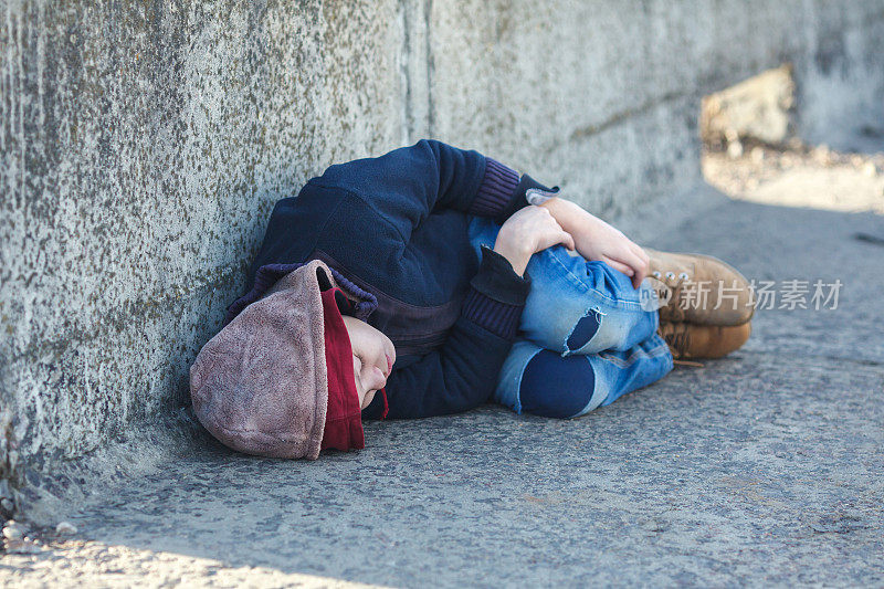 无家可归的小男孩睡在桥上