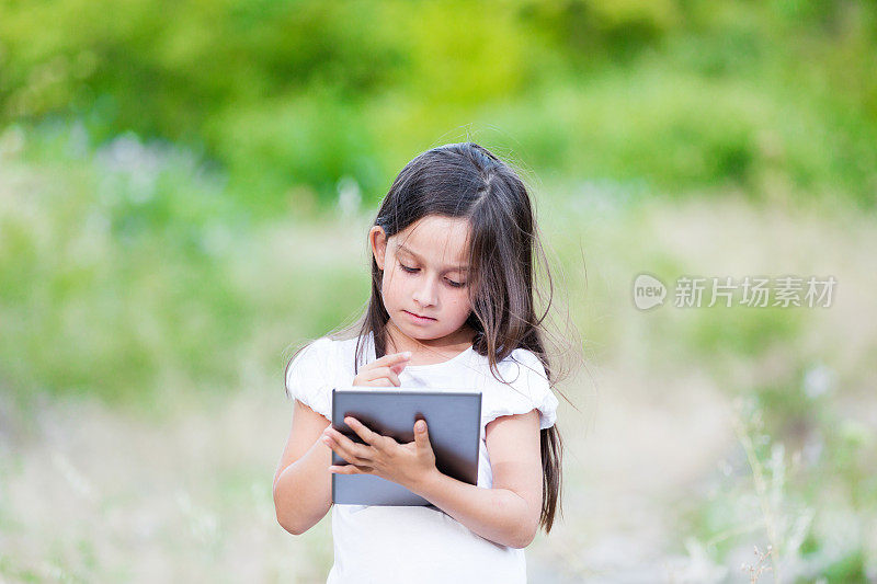 小女孩在树林里玩平板电脑