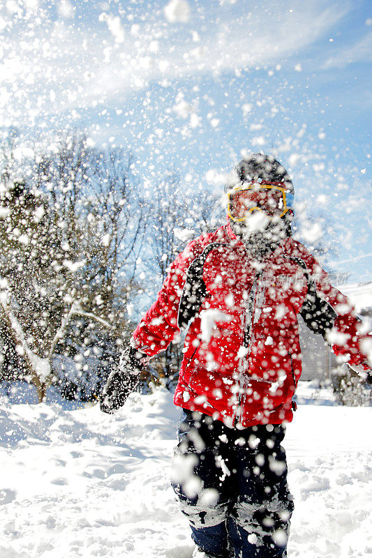 在打雪仗中，穿红色夹克的男孩扔雪球