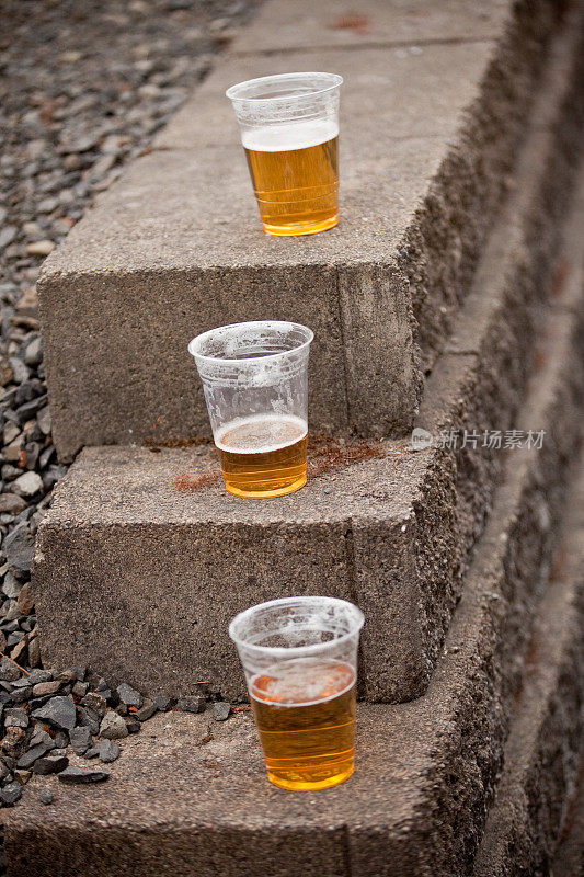 三个塑料杯啤酒放在石头上