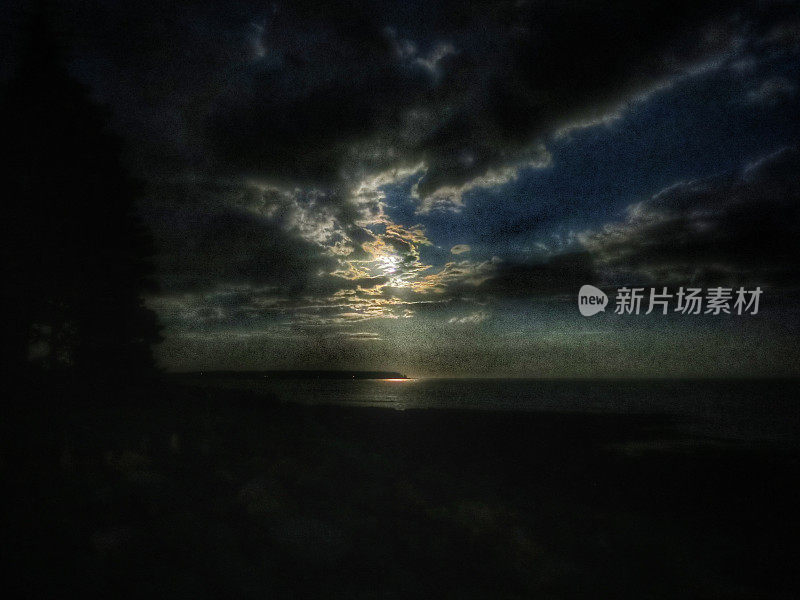 午夜天空，满月发光的云反射在海洋上