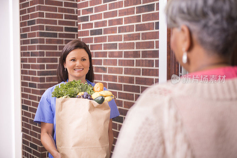 志愿服务:一名妇女在家中为老年妇女送杂货。