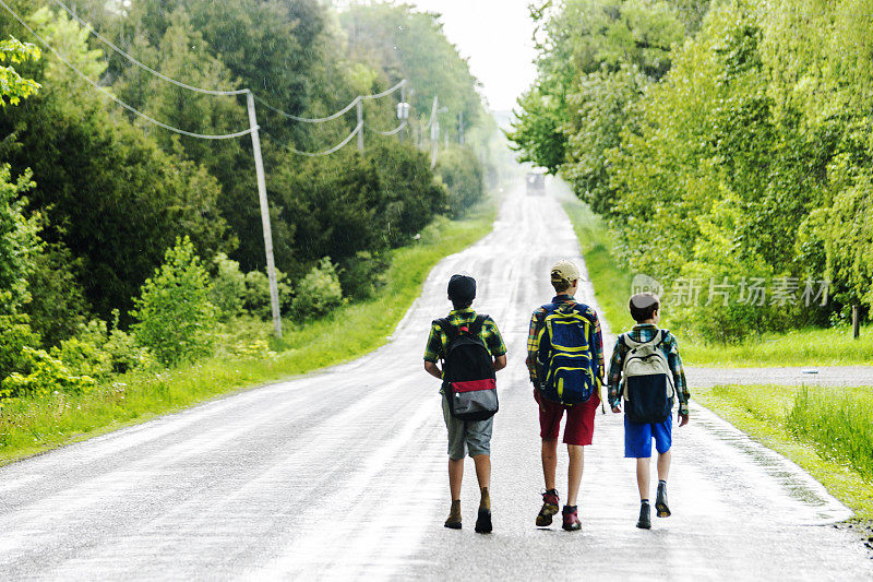 三个男孩在乡村公路上搭便车