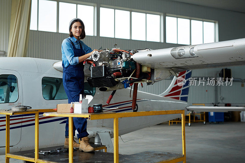 年轻女子在机库修理飞机