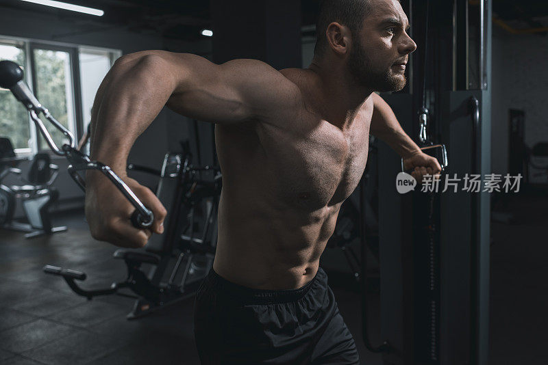 肌肉发达的运动员在健身房用运动器材锻炼