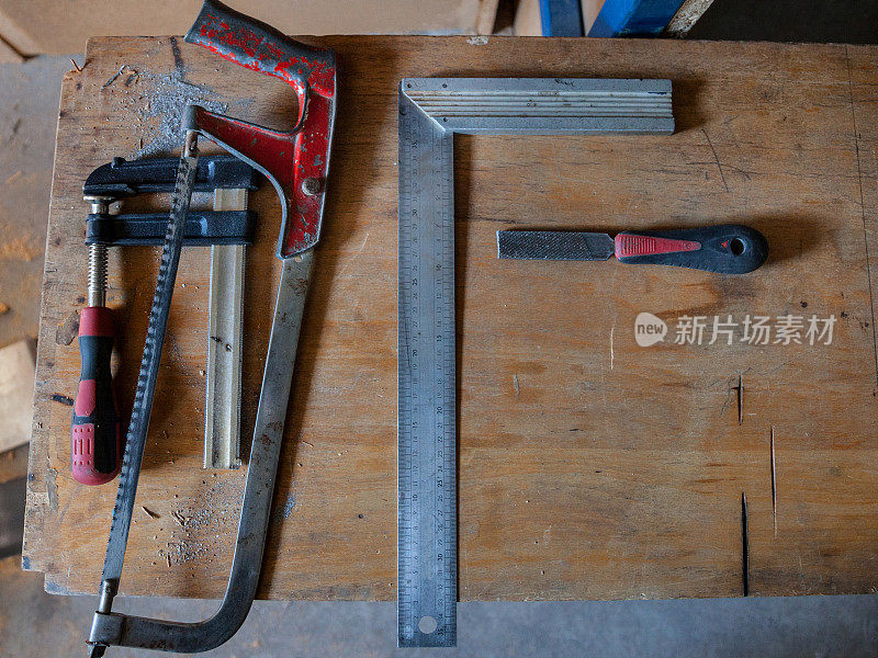 木工工具(丁字尺，钳子，锯子和锉刀)放在木工作台上