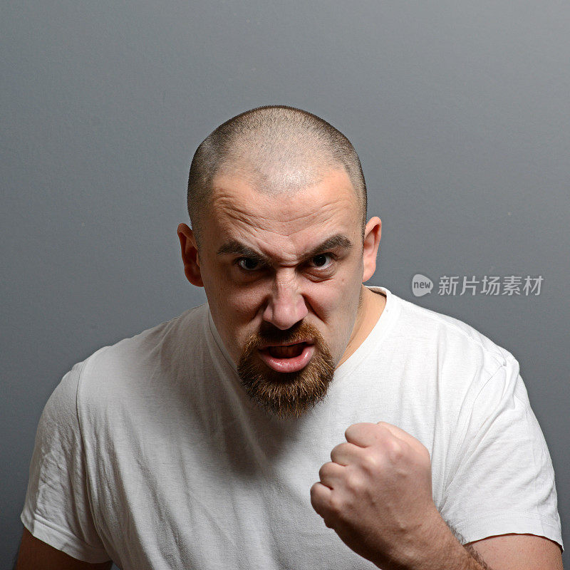 一个愤怒的男人在灰色背景下紧握拳头的肖像