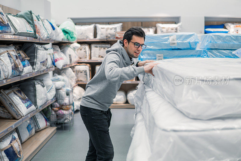 顾客男士在超市商场选购床上用品。