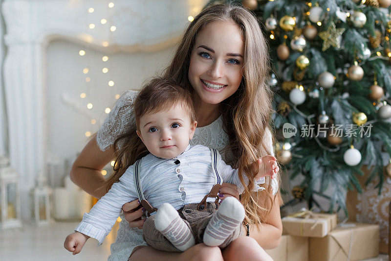 妈妈带着一个小儿子在他房子里的一棵漂亮的圣诞树旁