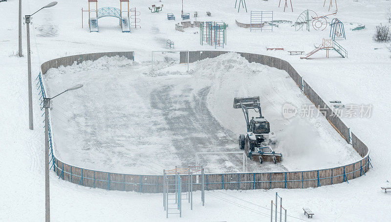 拖拉机清除操场溜冰场上的积雪