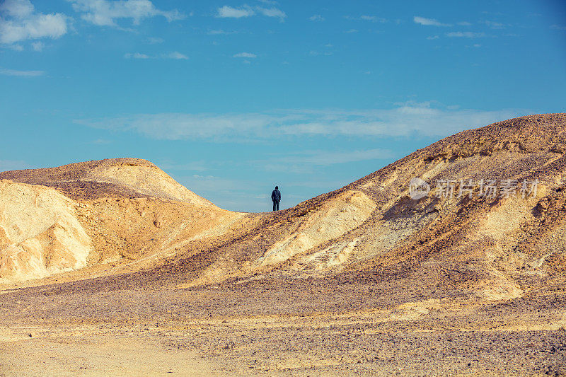沙漠景观。一个人站在沙漠的山上