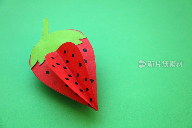 折纸草莓与绿色背景