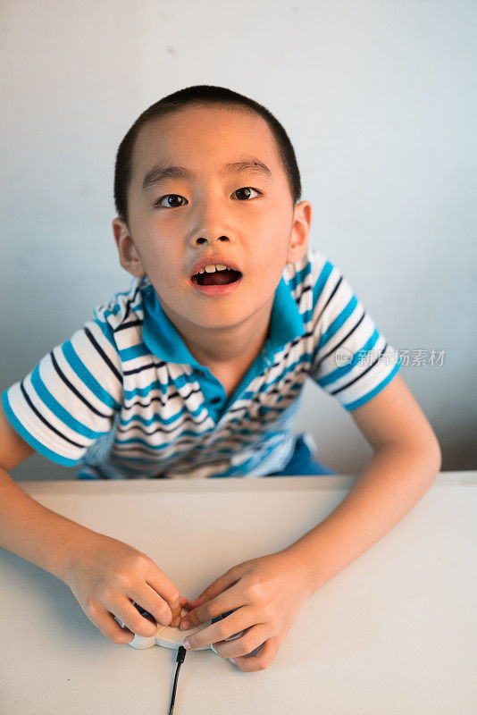 亚洲男孩与玩把手在桌子上看着相机