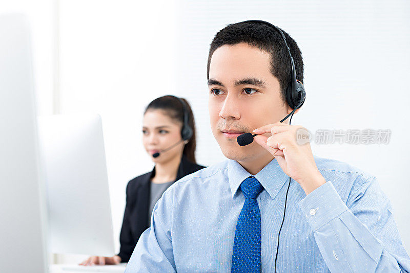 英俊的亚洲男性电话销售客服在呼叫中心工作