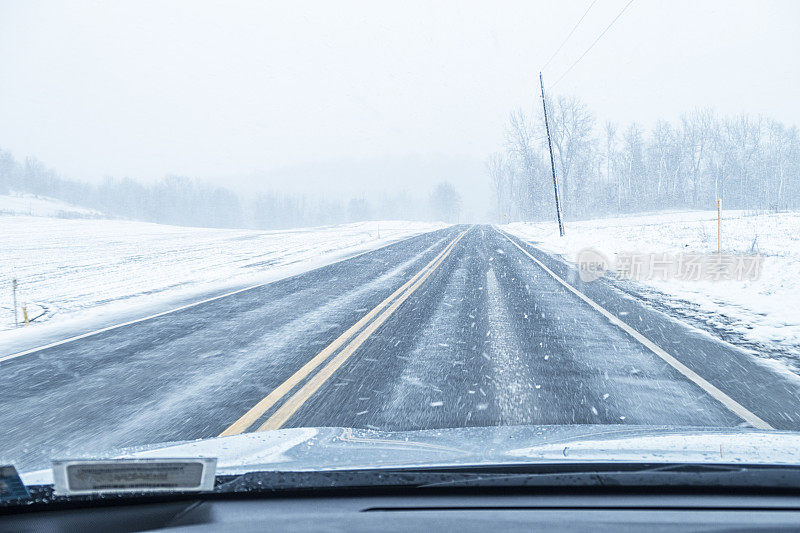 湿滑的乡村公路汽车在冬季暴风雪中行驶的观点