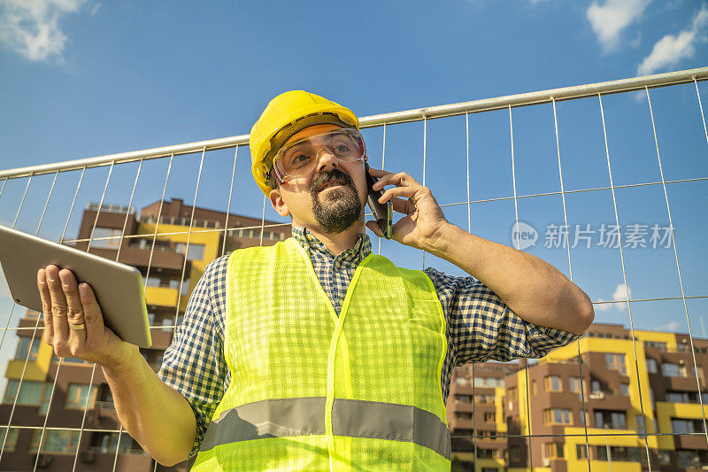 工人、建筑师或建筑工程师在建筑工地打电话