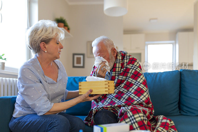当她们坐在客厅的沙发上时，一位老妇人帮助生病的丈夫。她给他吃药，照顾他。