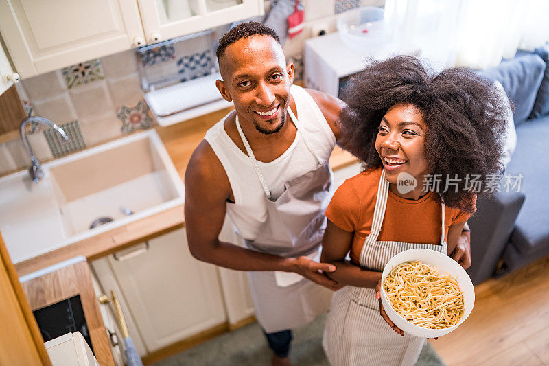 幸福的情侣在烹饪食物和展示他们的感情