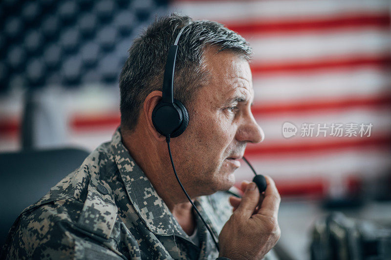 一位老兵坐在办公室里，戴着耳机和麦克风