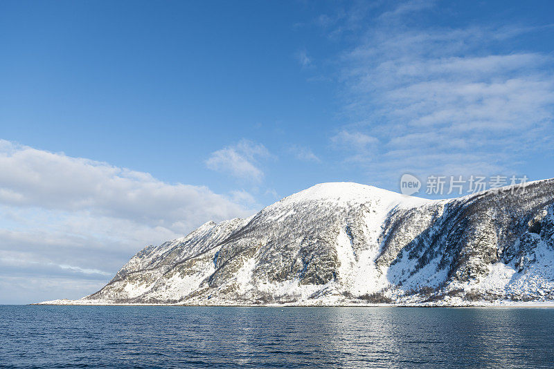 阳光照在雪山上，从挪威北部Senja的海面升起