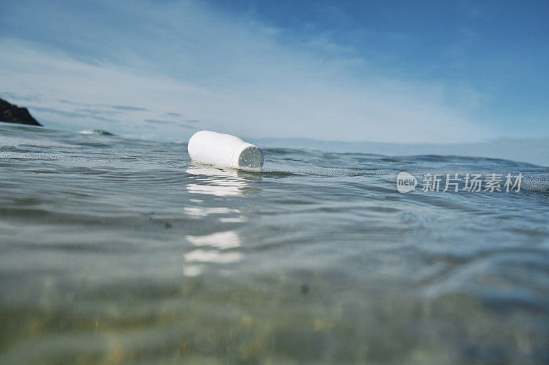 白色的废弃塑料瓶漂浮在海面上。