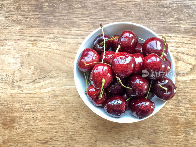 新鲜的熟樱桃在一个碗横跨木制背景。前视图。夏天的概念。本空间