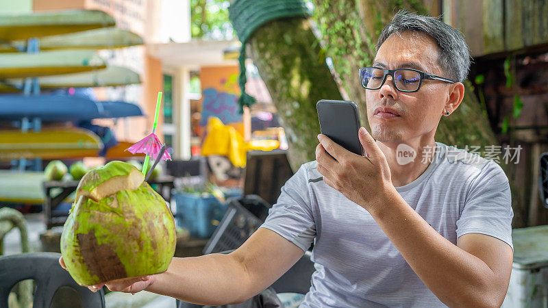 一个成熟的男人在给椰子拍照