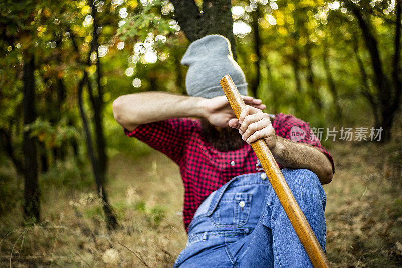 年轻人在砍柴时休息伐木工人森林里的一个伐木工人每天都在准备和砍柴