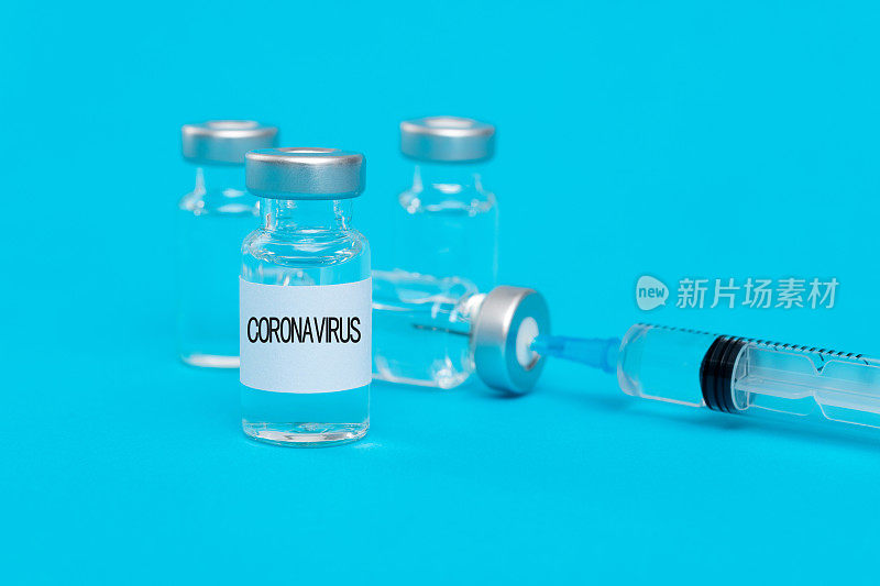 蓝色背景的注射器和冠状病毒疫苗瓶